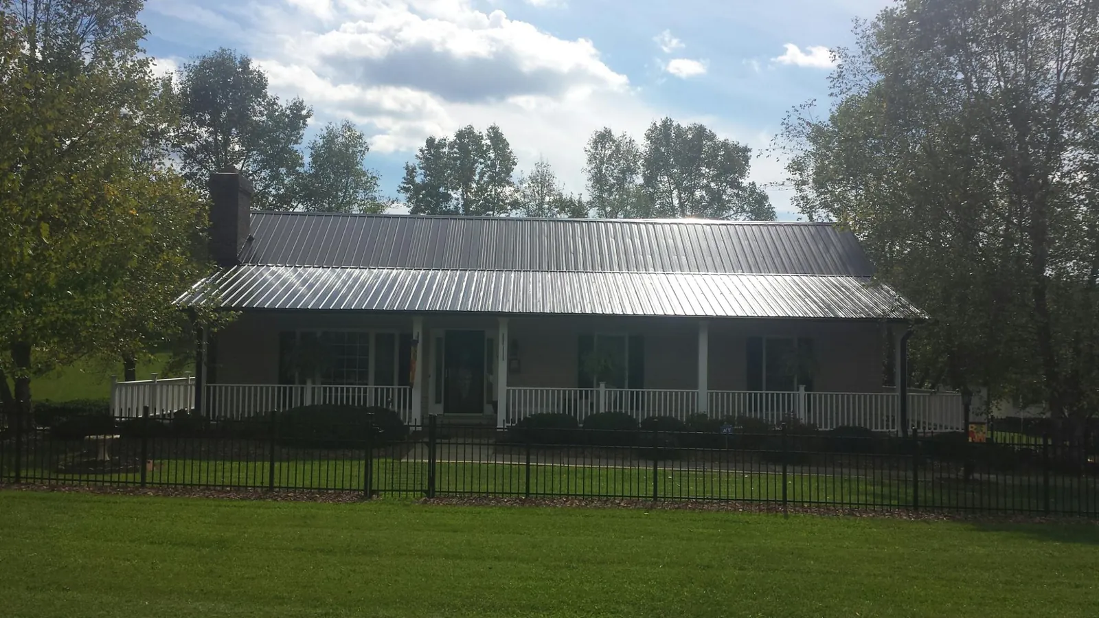 Gray metal roof on a brick ranch with a full width front porch — Gutter Guard Installation work by our crew in Rainier