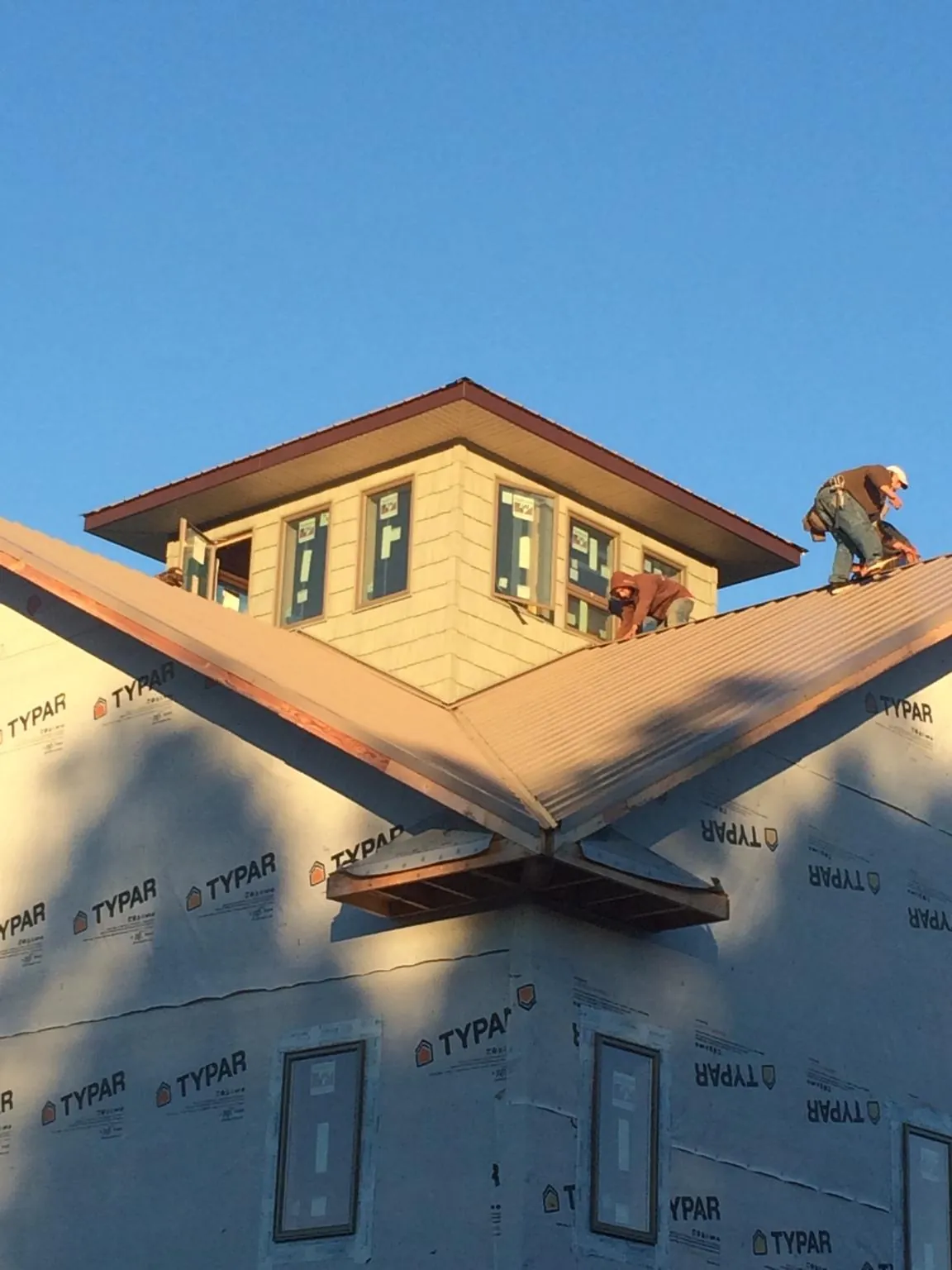 Roofers working around a rooftop cupola on a new metal roof at sunset — Roof Waterproofing in Rainier by Roofing Brothers